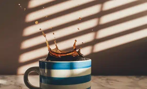 A blue and white striped cup with coffee splashing