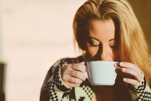 A blonde woman sipping a cup of coffee