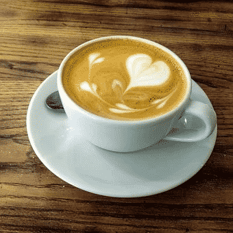 A white cup full of coffee with latte art on the shape of hearts on top