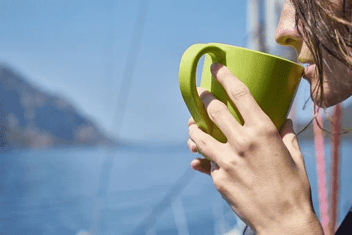 A women sipping from a green coffee mug