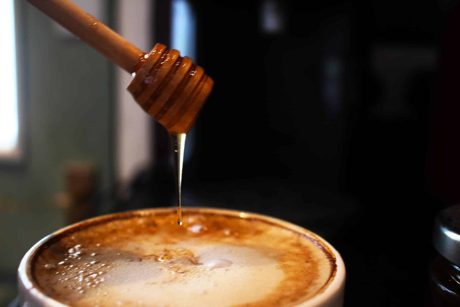 Pouring honey in coffee to sweeten it